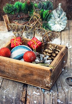 Wooden box full of Christmas toys and cones on wooden background.Selective focus