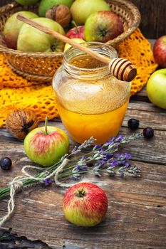 Autumn harvest of apples in the background of the glass jar with fragrant honey.Photo tinted