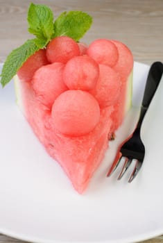 piece of watermelon with watermelon balls and mint on a plate