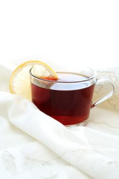 Morning pleasure. Cup of black tea with lemon on white cloth