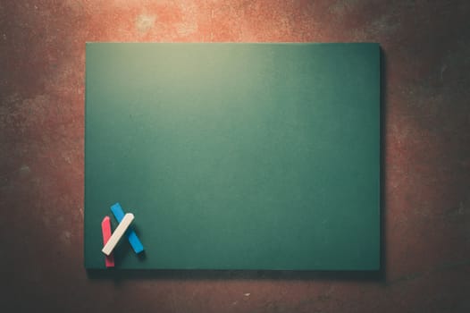 Small black board in green color with blank space for text or message on veteran red cement background with low key scene and vintage filter effect