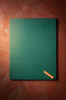 Small black board in green color with blank space for text or message on veteran red cement background with low key scene