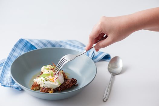Woman right hand with fork stab on hash brown with Halloumi cheese and savory dressing