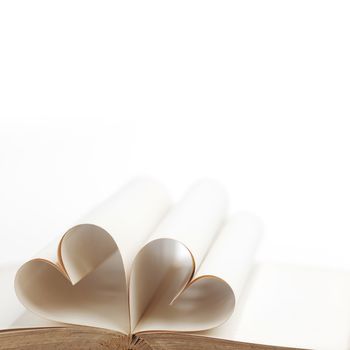 Pages of open book rolled in heart shape isolated on white