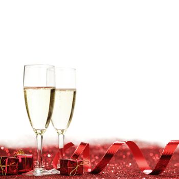 Glasses with Champagne and gifts on red glitters isolated on white background