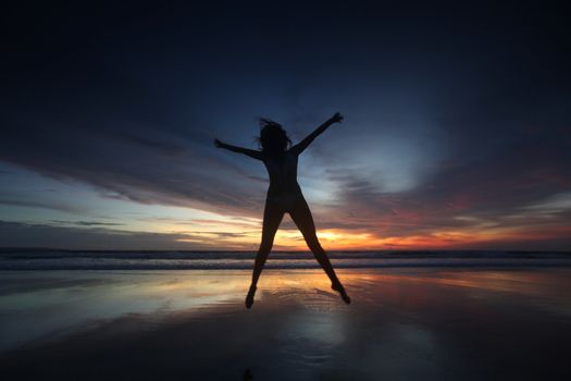 Happy woman jumping on the beach at sunset, Bali, Seminyak, Double six beach
