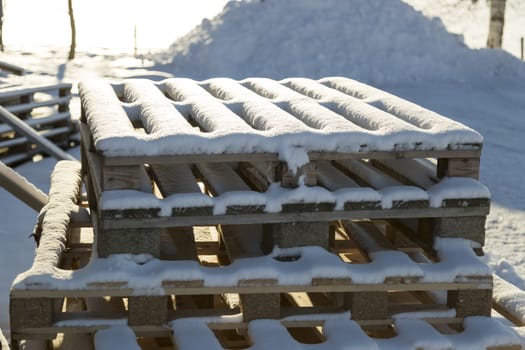 Box Pallets Covered in Snow stacked on top of each other.