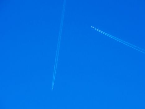 Aeroplanes flying through clear blue sky with vapour trails