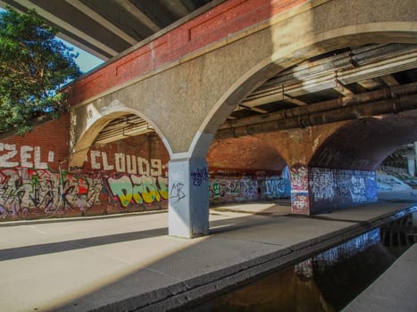 Under a storm drain bridge covered with graffitti