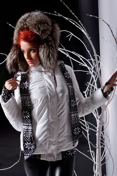 Young beautiful woman in fashionable clothing on a studio background with branches