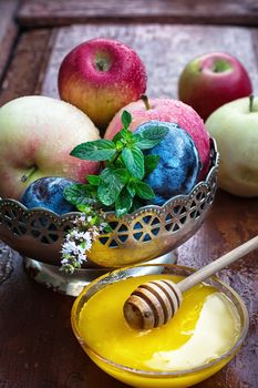 apples and plums in iron vase and saucer with fresh honey