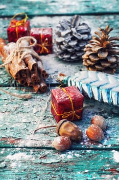 Gifts and decorations for Christmas on wooden background strewn with pine cones and spices