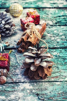 Gifts and decorations for Christmas on wooden background strewn with pine cones and spices