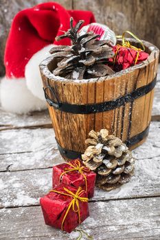 wooden tub filled with pine cones and Christmas ornaments on  background of snow