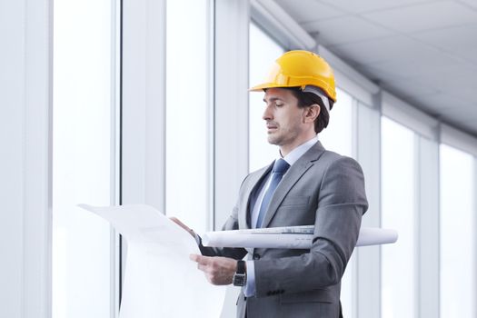 Architector in hardhat and business suit with construction plans