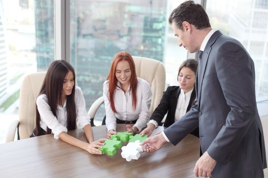 Group of business people assembling jigsaw puzzle and represent team support and help concept in office