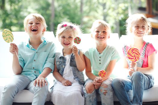 Group of happy smiling children with lollipops outdoors