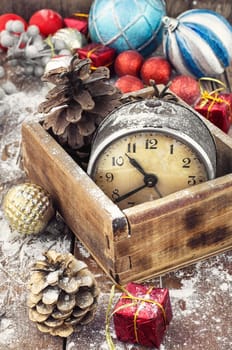 outdated watch in wooden box on the background of Christmas decorations and pine cones.Photo tinted.