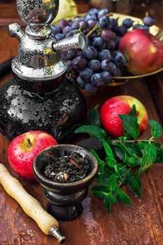 Hookah with fruit flavour on wooden table in vintage style