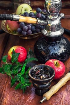 Hookah with fruit flavour on wooden table in vintage style
