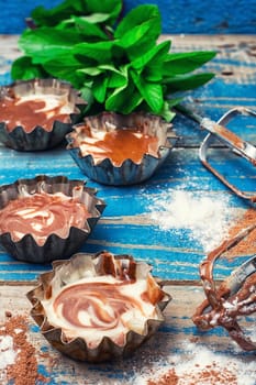 Baked chocolate cupcakes in tins on wooden table