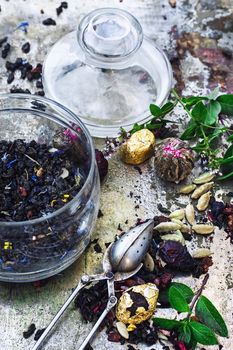 Various dry tea brew on iron background with tea paraphernalia.
