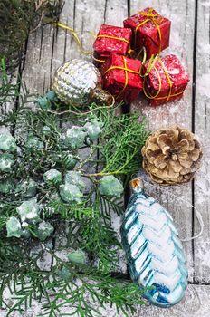 Christmas decorations under the branches of fir tree on  snowy wood plank