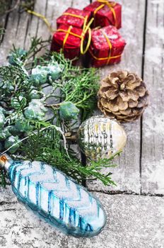 Christmas decorations under the branches of fir tree on  snowy wood plank