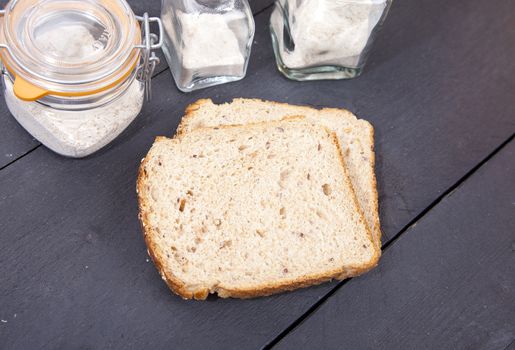 Gluten free bread with spelled flower on black wooden background