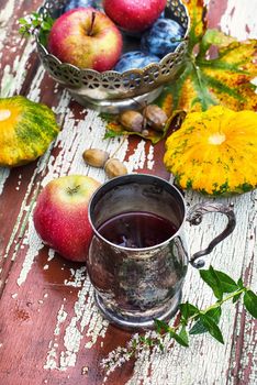 mug with herbal tea on  background of apples and plums in the autumn garden