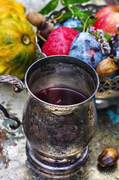 mug with herbal tea on  background of apples and plums in the autumn garden