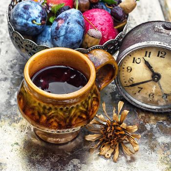 clay mug with herbal tea on  background of apples and plums in the autumn garden