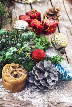 Christmas decorations under the branches of fir tree on  snowy wood plank
