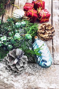 Christmas decorations under the branches of fir tree on  snowy wood plank