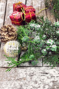 Christmas decorations under the branches of fir tree on  snowy wood plank