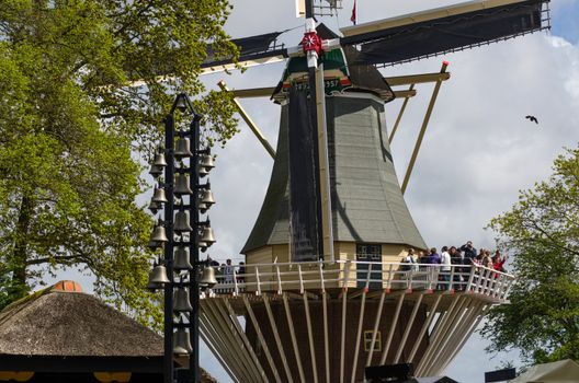 Lisse, The Netherlands - May 7, 2015: Old windmill with many tourists in famous garden in Keukenhof. Keukenhof is the most beautiful spring garden in the world.