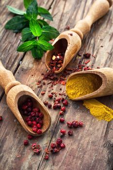 Three wooden shovel with a variety of spices on wooden background in rustic style