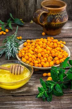 Ripe berries of sea buckthorn in  saucer on wooden background