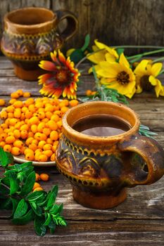 Ripe berries of sea buckthorn in  saucer on wooden background
