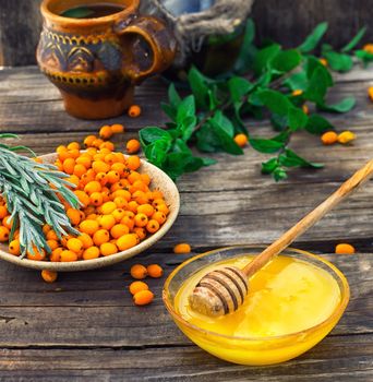 Ripe berries of sea buckthorn in  saucer on wooden background