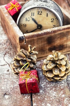 outdated watch in wooden box on the background of Christmas decorations and pine cones.Photo tinted.