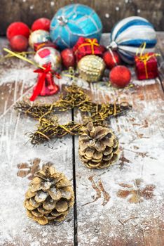 Two pine cones on the background of snow-covered Christmas ornaments