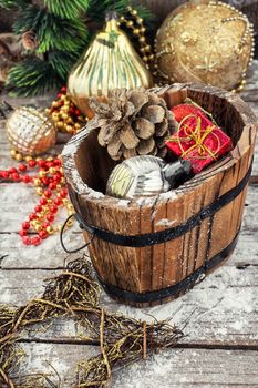 Decorative wooden tub filled with Christmas ornaments and pine cones
