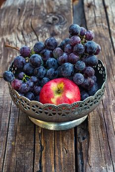 Brush ripe and juicy grapes in  vintage iron vase on wooden background