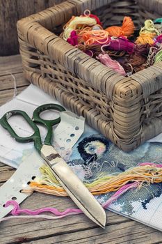Yarn and thread for embroidering on cloth by hand on a wooden surface.Tinted