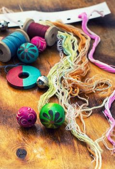 Yarn and thread for embroidering on cloth by hand on a wooden surface.Tinted