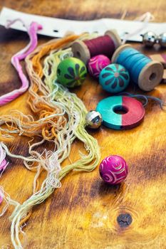 Yarn and thread for embroidering on cloth by hand on a wooden surface.Tinted