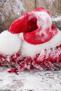 Red Christmas hat on snow-covered wooden table