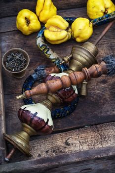 Stylish hookah disassembled in wooden box with fragrant autumn fruit quince.