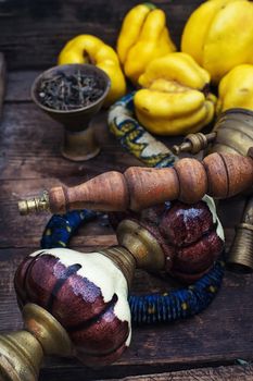 Stylish hookah disassembled in wooden box with fragrant autumn fruit quince.